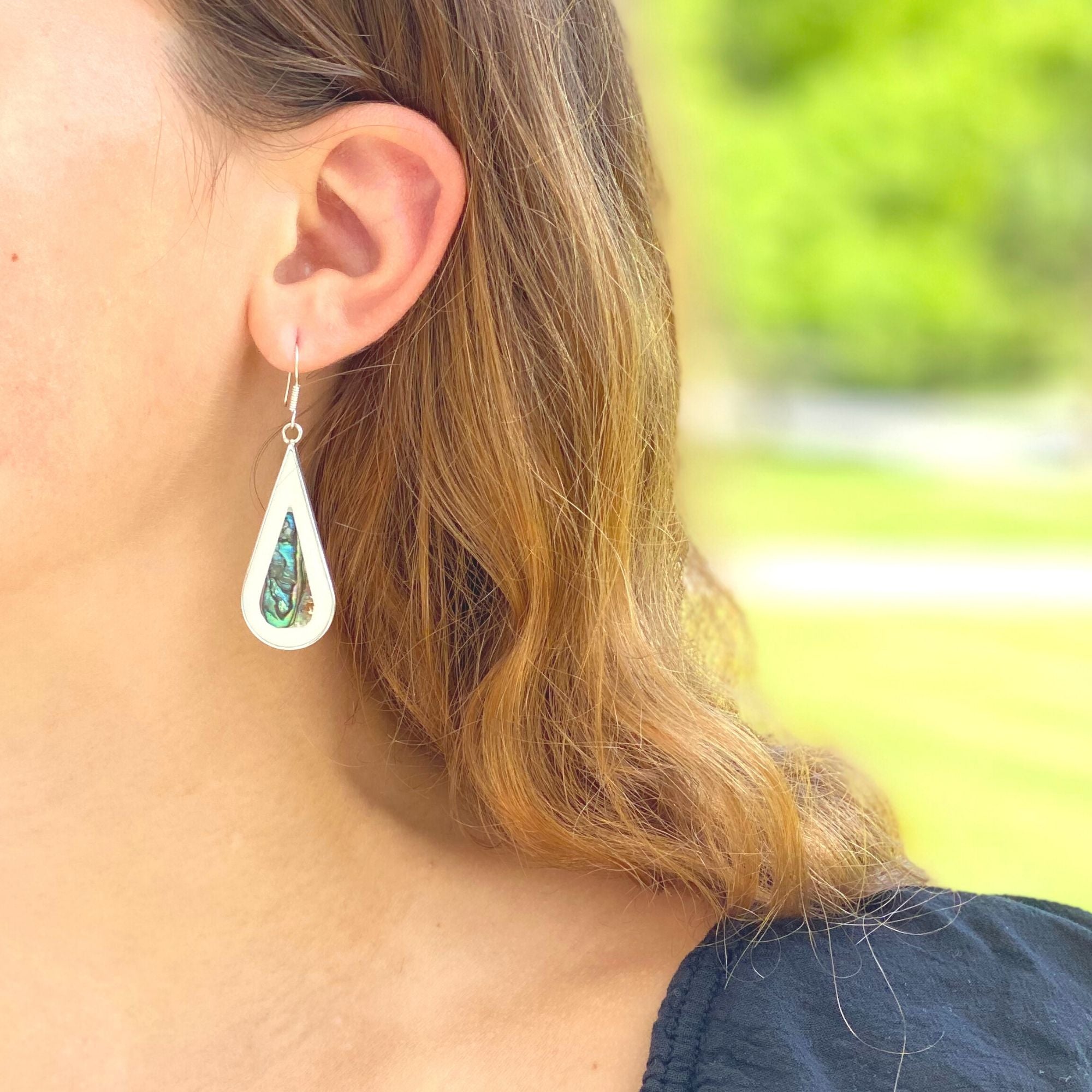 A model wearing sterling silver abalone and Mother-of-Pearl shell earrings.