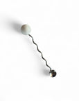 Metallic drink stirrer with a marble spherical end on a white background