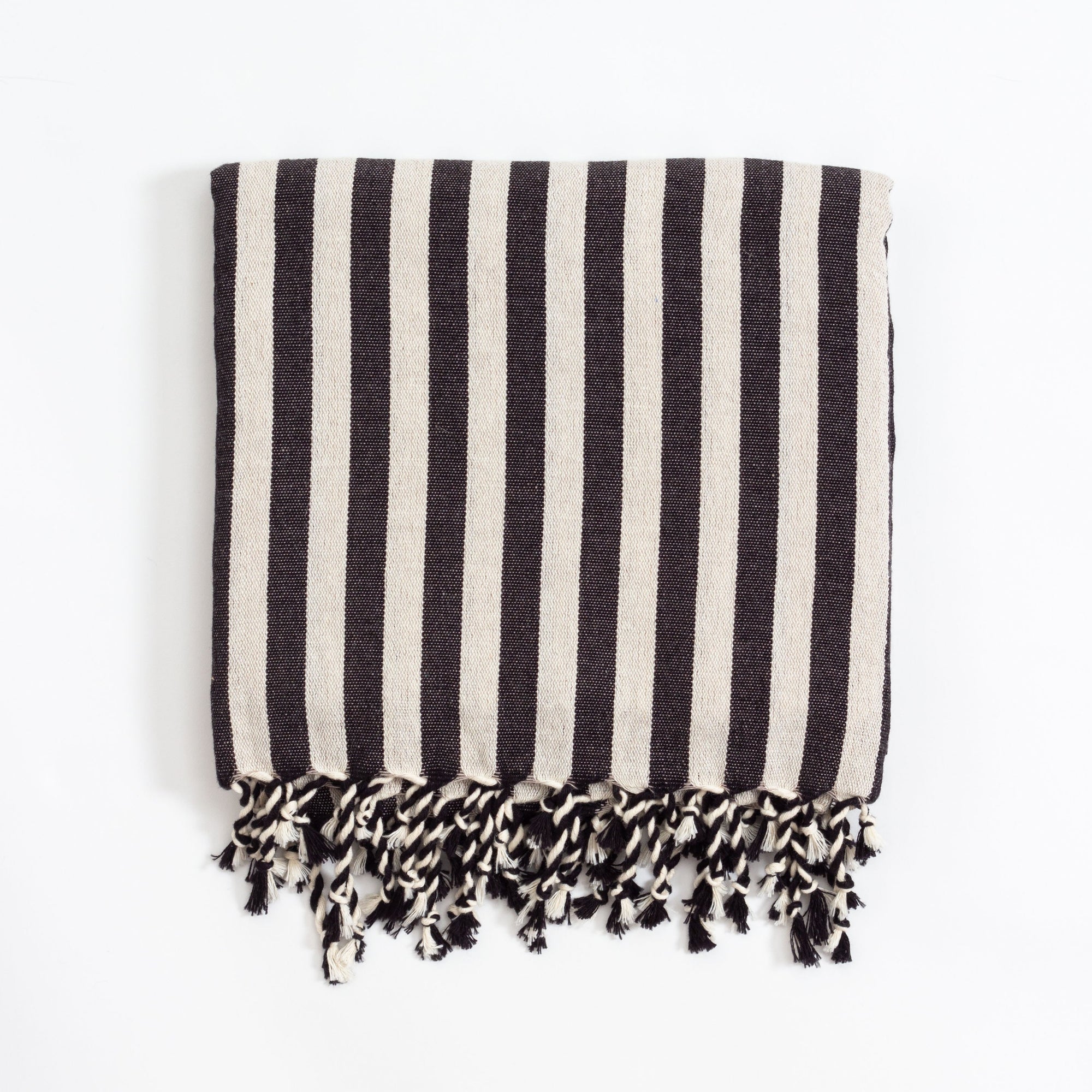 A black and white striped Turkish bath towel with fringes on the ends.