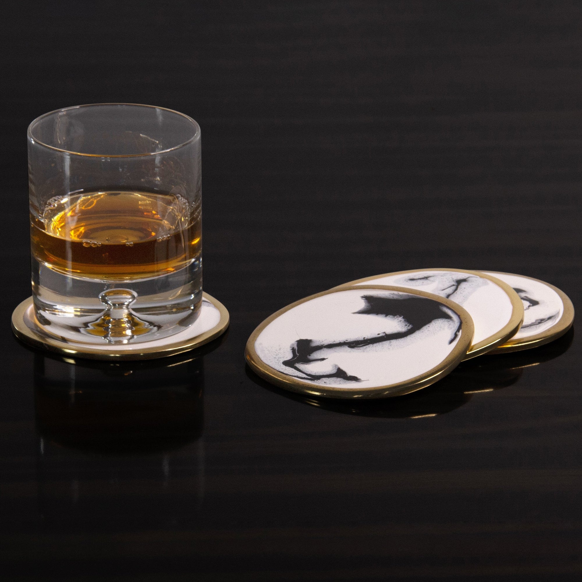 Glass of whiskey on a coaster with decorative coasters in the background