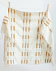 Plaid hand towel with white and brown pattern hanging on a clothesline against a white background