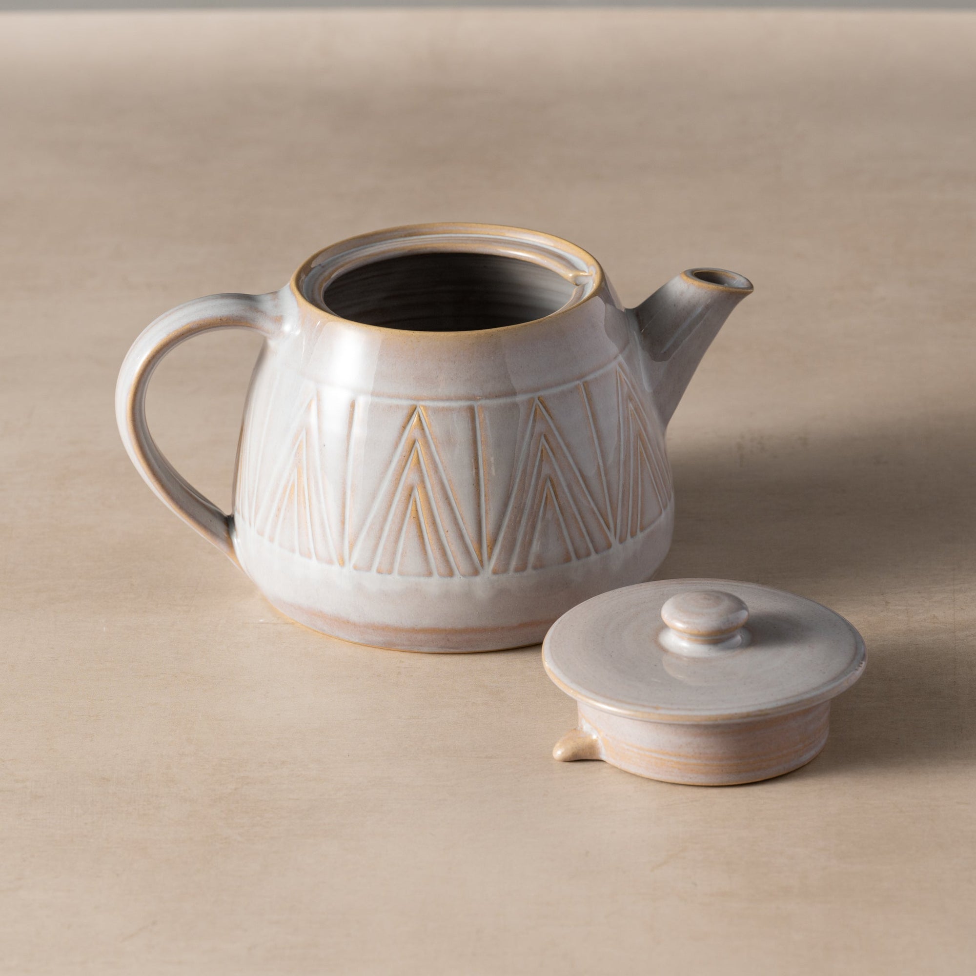 Ceramic teapot with geometric design on a beige background