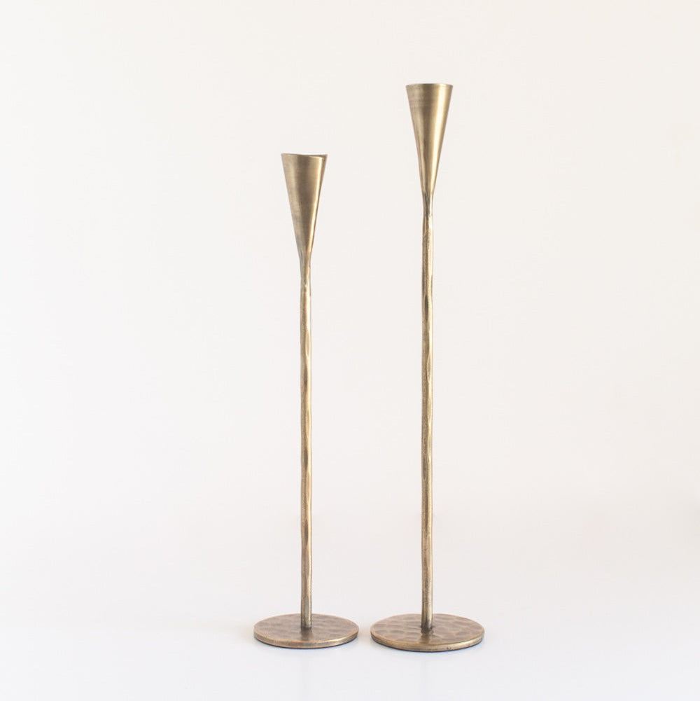 Two brass candleholders on a white background
