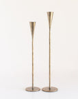 Two brass candleholders on a white background