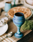 Blue swirled goblet on a wooden table with a blurred background