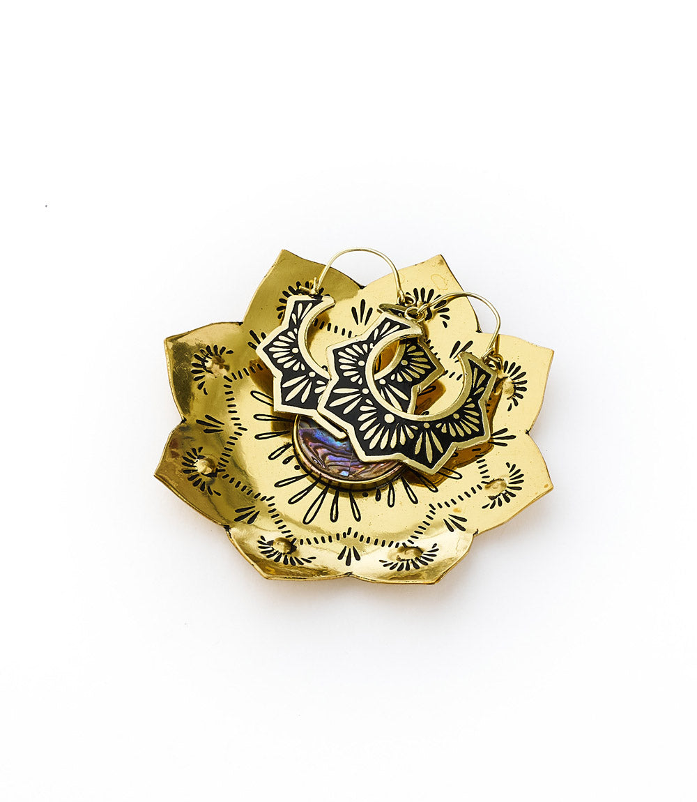 A brass tray with a lotus design holding two rings