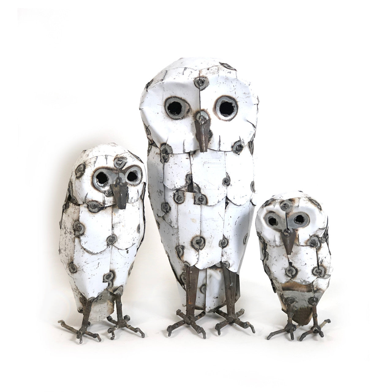 A set of three white recycled metal owl sculptures of varying sizes perched together