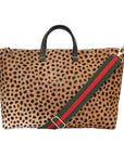 A leopard print hair-calf leather weekender bag with a roomy design and a black handle and a red and green strap.