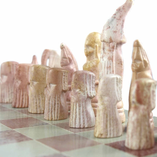 Hand-carved soapstone Maasai chess set on a 14-inch square board, with pieces in pink and white soapstone zoomed in on the pink soapstone pieces.