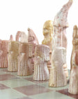 Hand-carved soapstone Maasai chess set on a 14-inch square board, with pieces in pink and white soapstone zoomed in on the pink soapstone pieces.