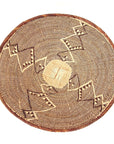 A large, handcrafted basket with a herringbone pattern and a coiled rim, made from natural fibers in a brown color