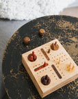 A hand-carved wooden Pachisi game set with a hinged lid, game peg pieces, and dice on a wooden stool.