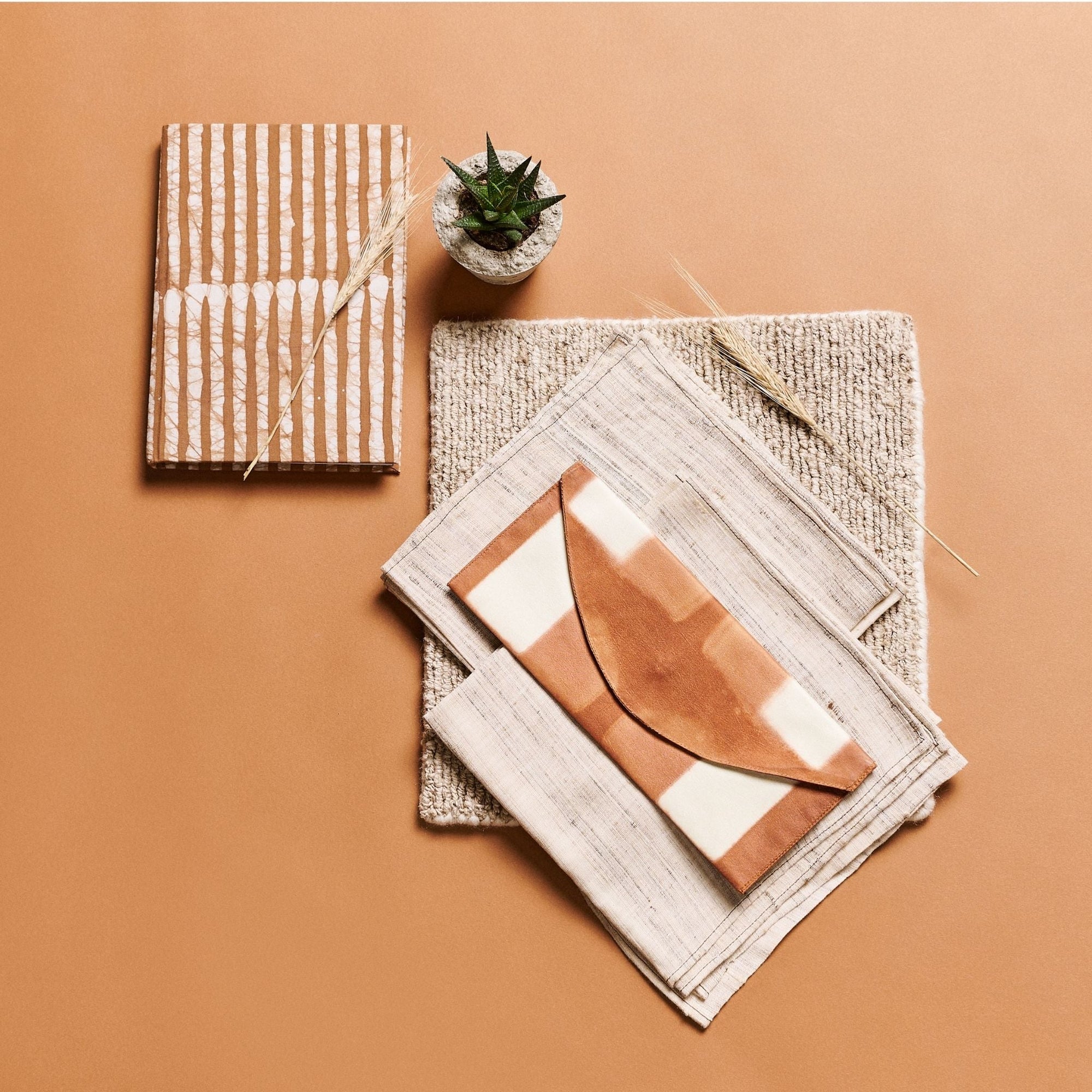 Decorative items including a notebook, a small plant, and a folded fabric on a brown background
