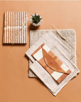 Decorative items including a notebook, a small plant, and a folded fabric on a brown background
