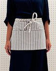 A person wearing a striped waist apron with pockets.