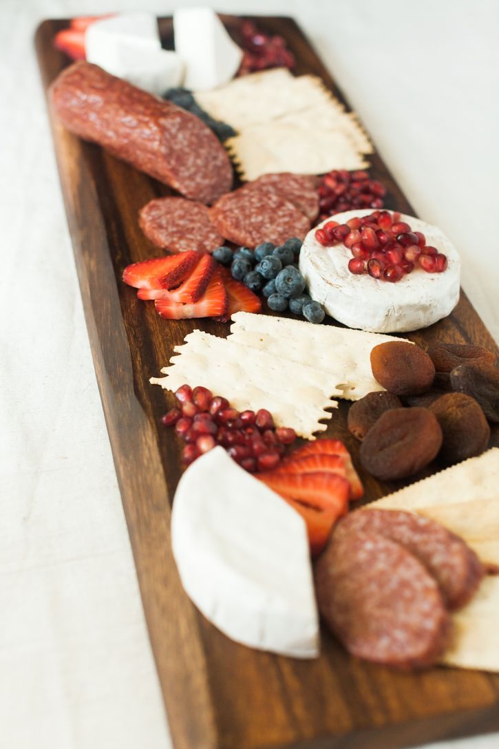 Wooden charcuterie board with assorted cheeses, fruits, and meats