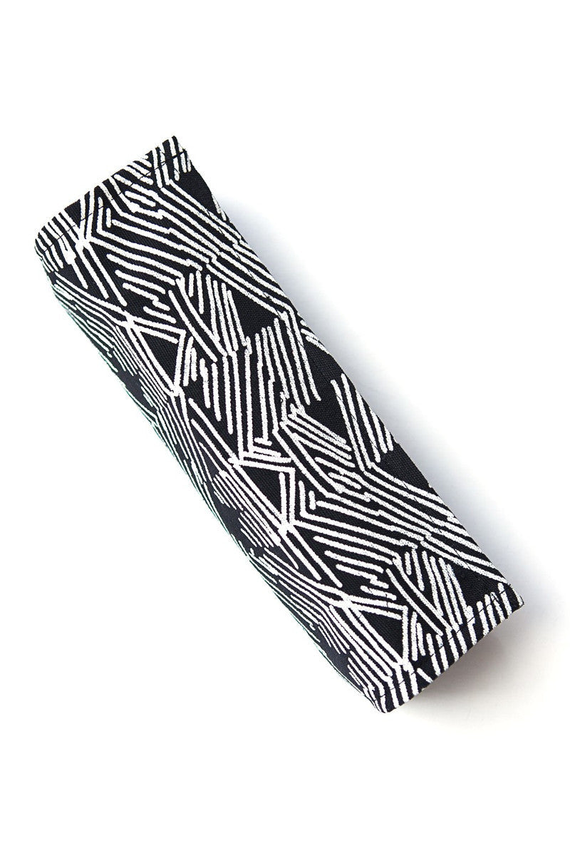 A closed jewelry roll travel case in a black matchstick design, unrolled to display compartments for earrings, rings, and necklaces.