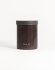 A brown soy wax candle in a reusable glass jar with the brand 'FIELD & Kit' visible on the jar, with a gray lid on top.