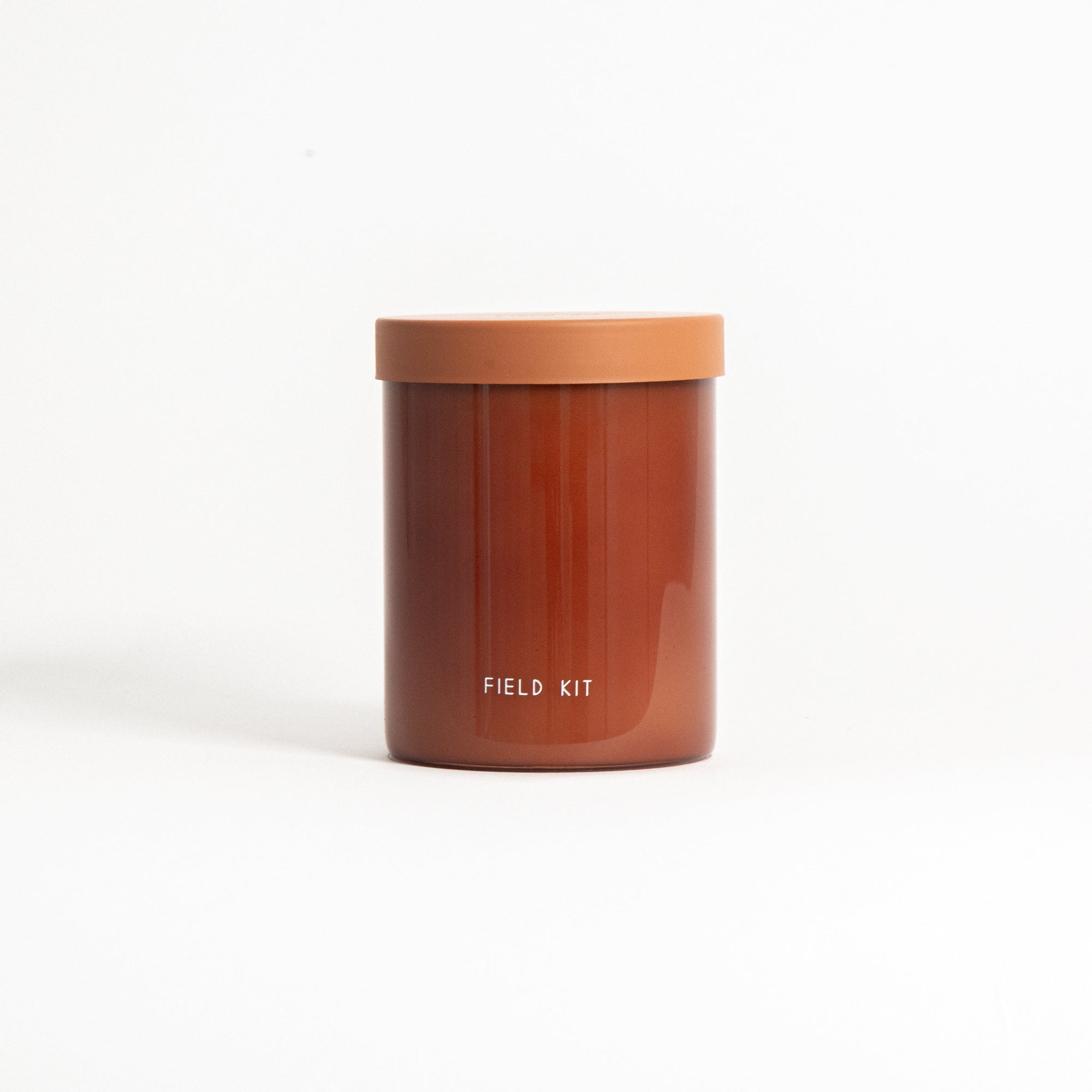 A brown soy wax candle in a reusable glass jar with a lid, labeled 'FIELD KIT'.