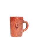 A brown ceramic mug with a protruding face and a handle, on a white background