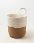 A woven basket in a two-tone color, with a natural palm upper section and a brown earthy lower section, displayed against a white background