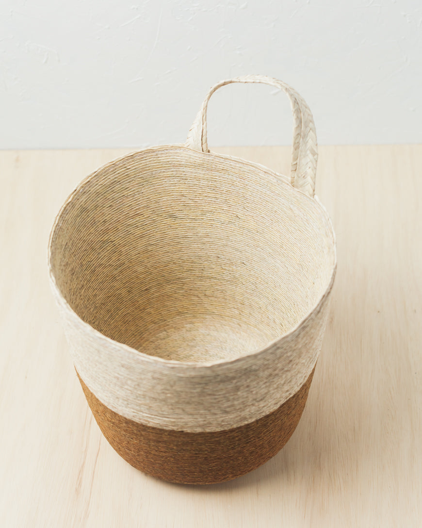 Woven basket with a handle on a light wooden surface