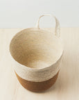 Woven basket with a handle on a light wooden surface