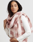 A model wearing a salmon pink wax block printed handwoven linen scarf with a white background.