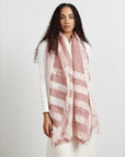 A model wearing a salmon pink wax block printed handwoven linen scarf with a gray background.