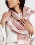 Up close of a model wearing a salmon pink wax block printed handwoven linen scarf with a white background.