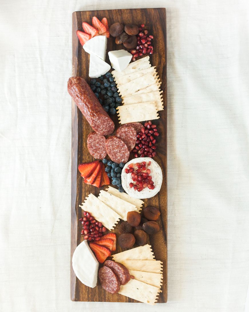 Charcuterie board with cheeses, meats, and fruits on a wooden board