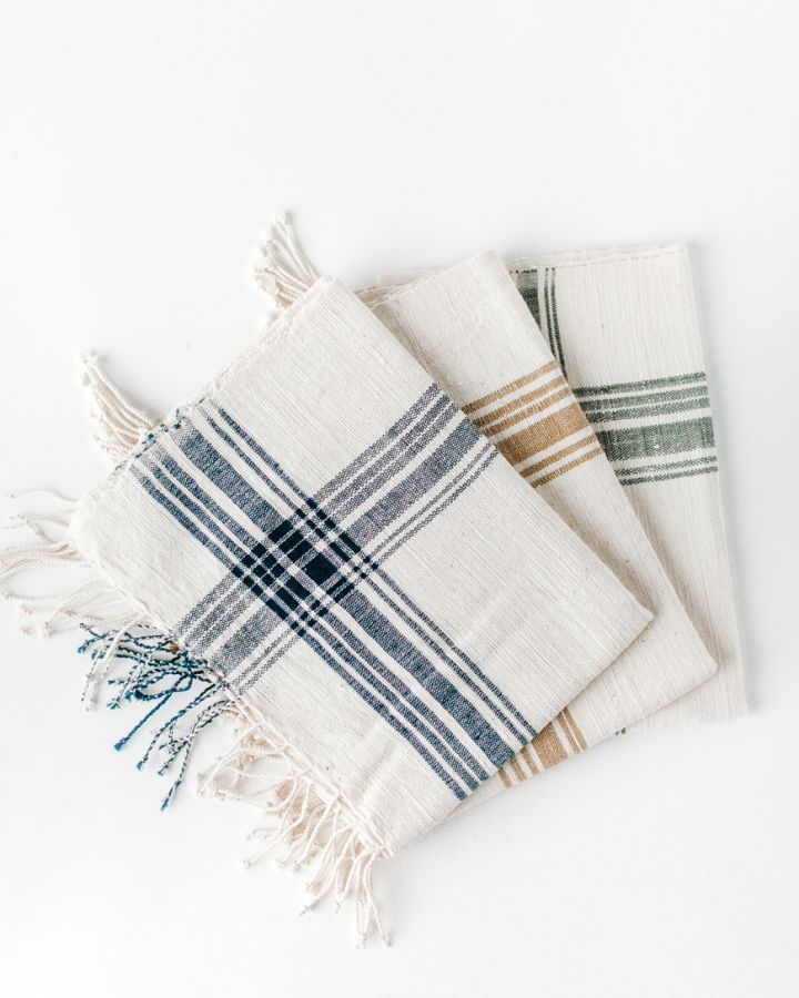 A set of folded striped hand towels with frayed edges on a white background.