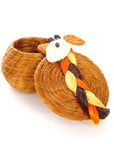 A handwoven brown lidded basket in the shape of a giraffe with a multicolored tail with the lid off