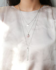A silver multi-strand multi-way pendant necklace with a pink chalcedony centerpiece stone on a model's neck.