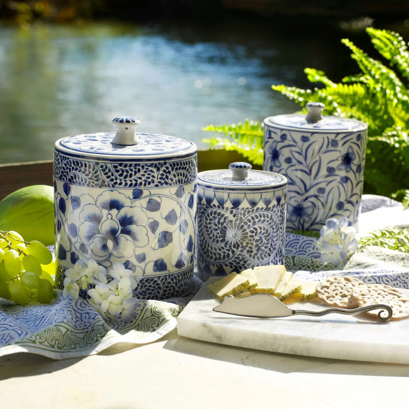 Set of blue and white ceramic canisters on a table with a scenic background