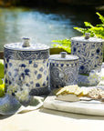 Set of blue and white ceramic canisters on a table with a scenic background