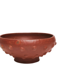 A handmade red clay decorative bowl with a textured exterior.