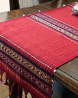 A red cotton table runner with a geometric design laid out on a wooden table