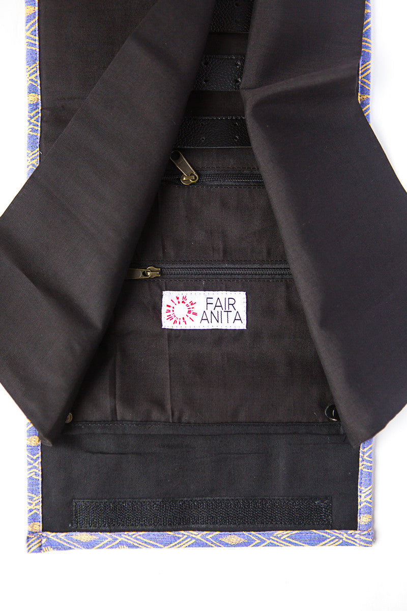 The inside compartments of a jewelry roll travel case with various compartments for earrings, rings, and necklaces, displayed alongside some jewelry items and a patterned fabric.