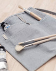 A blue waist apron with multiple pockets and a utility loop with paintbrushes inside the pockets.