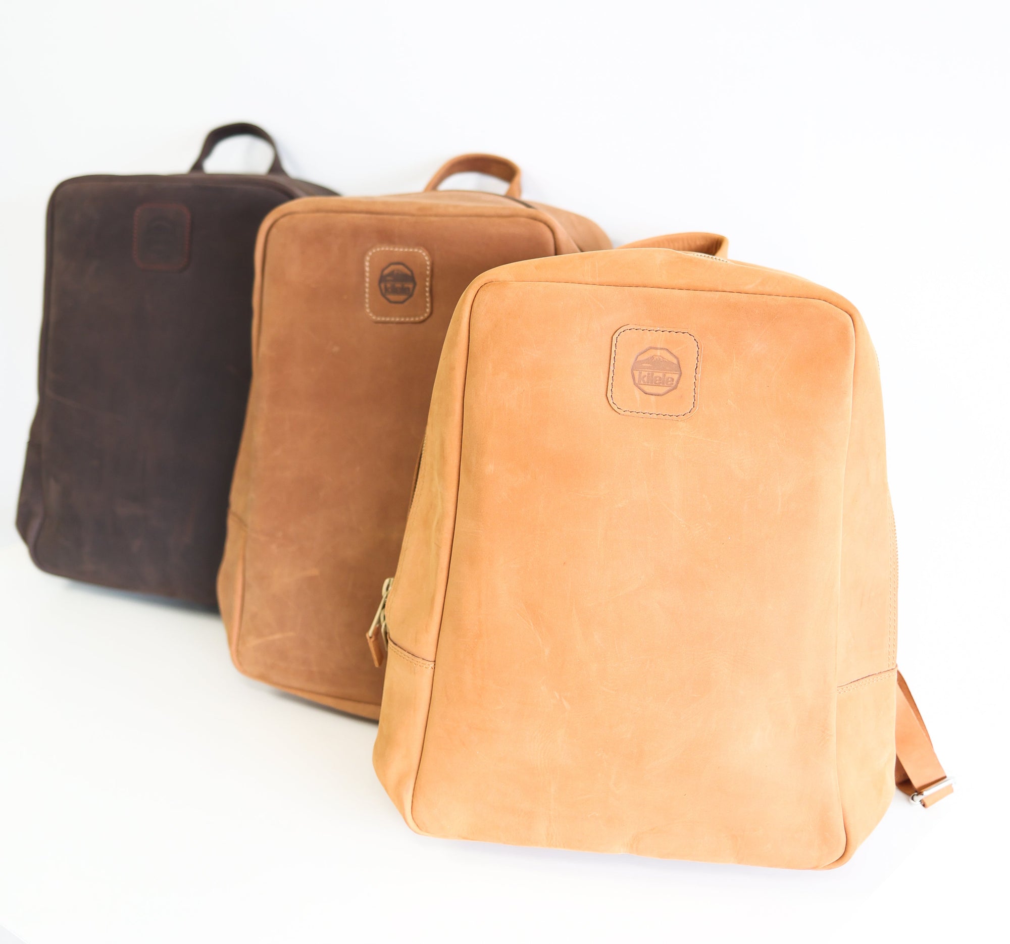 Set of handcrafted leather backpacks in rich earthy tones.