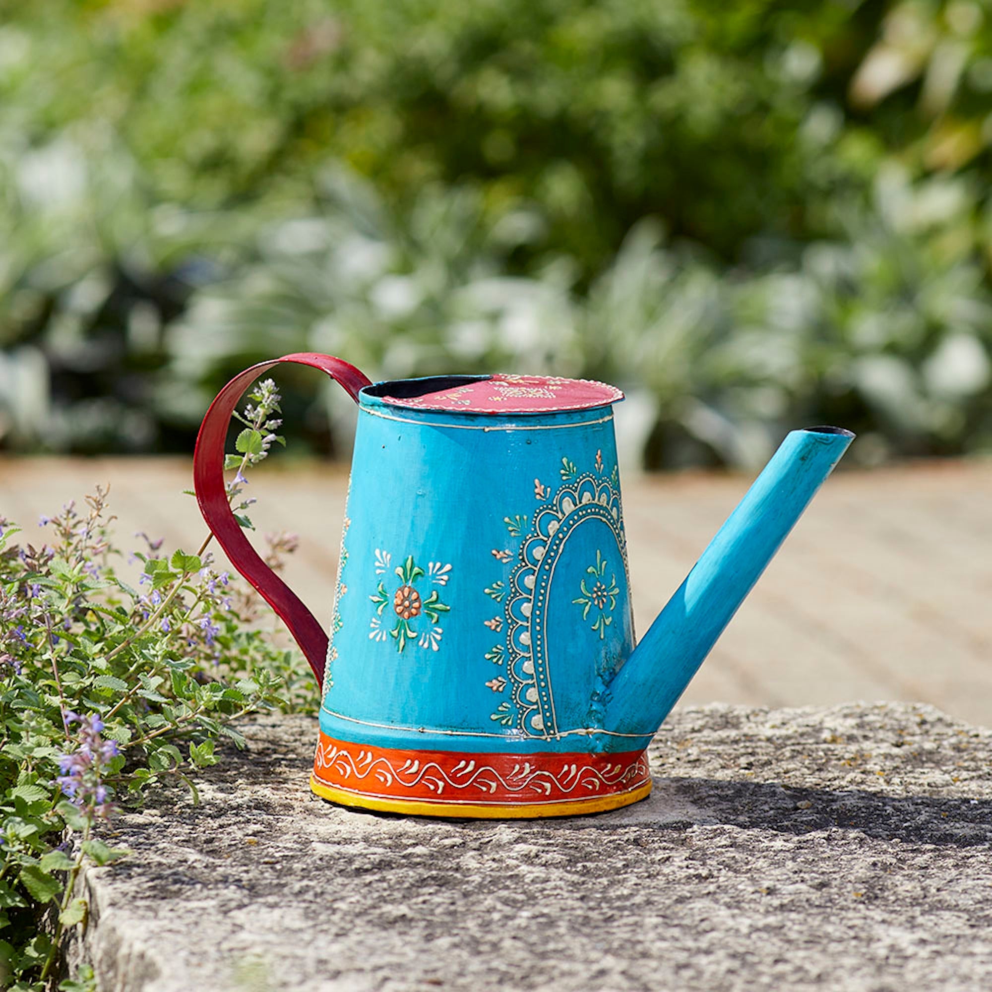 Blue and red floral watering can, handcrafted and painted for a colorful, functional addition to any garden.