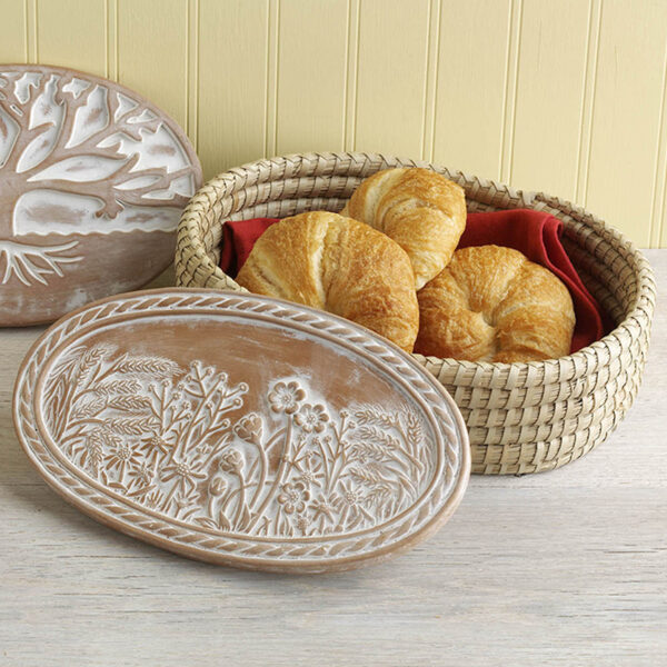 Bread served in a woven basket with a ceramic breadwarmer leaning against it—an inviting, artisan-made table presentation.