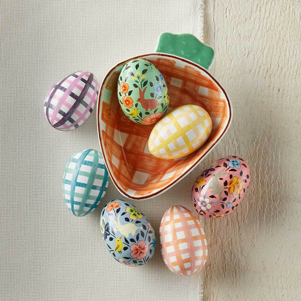 Easter eggs displayed inside a carrot-shaped dish on a light background.