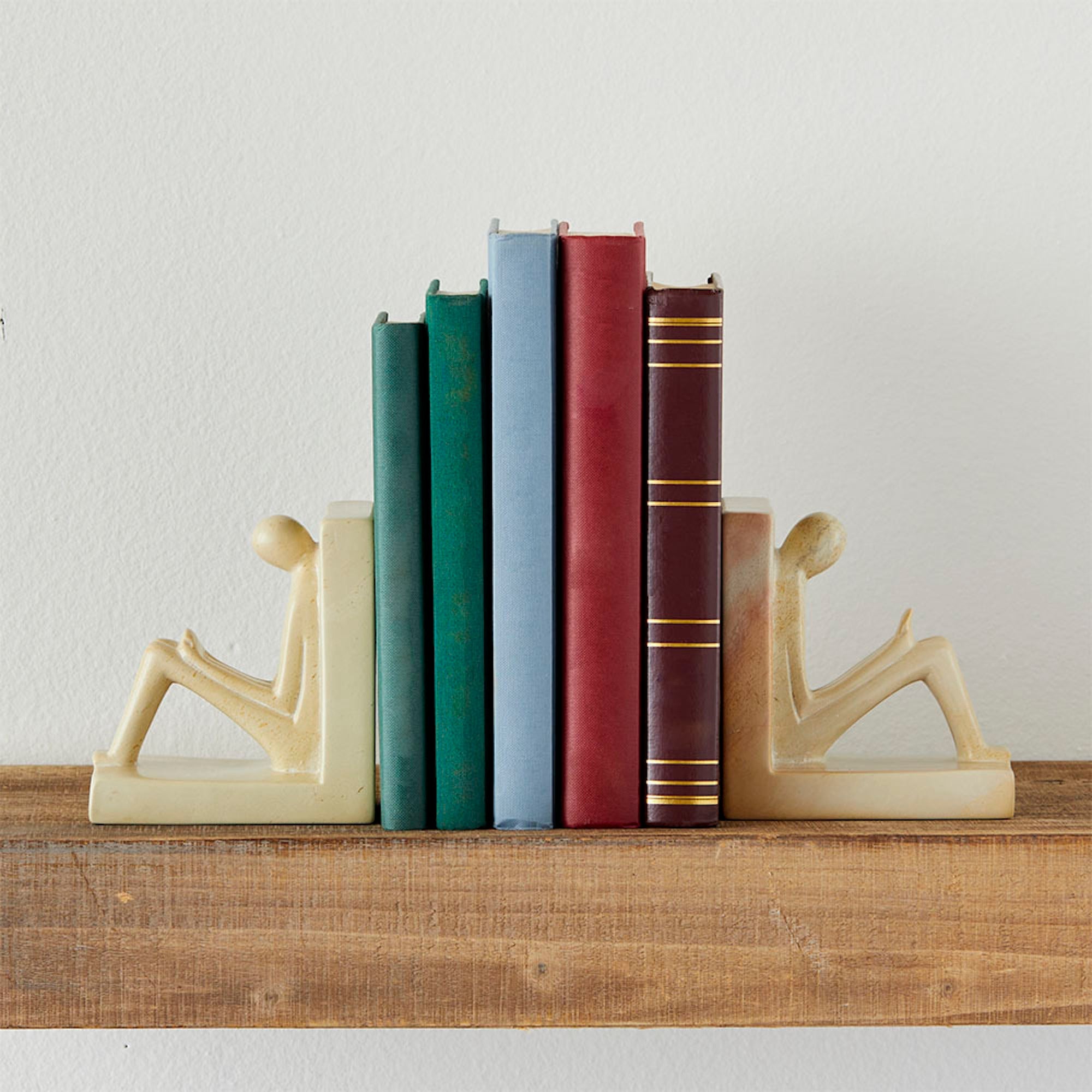 Stone bookends featuring figures reading books, hand-carved for a unique and functional shelf display.