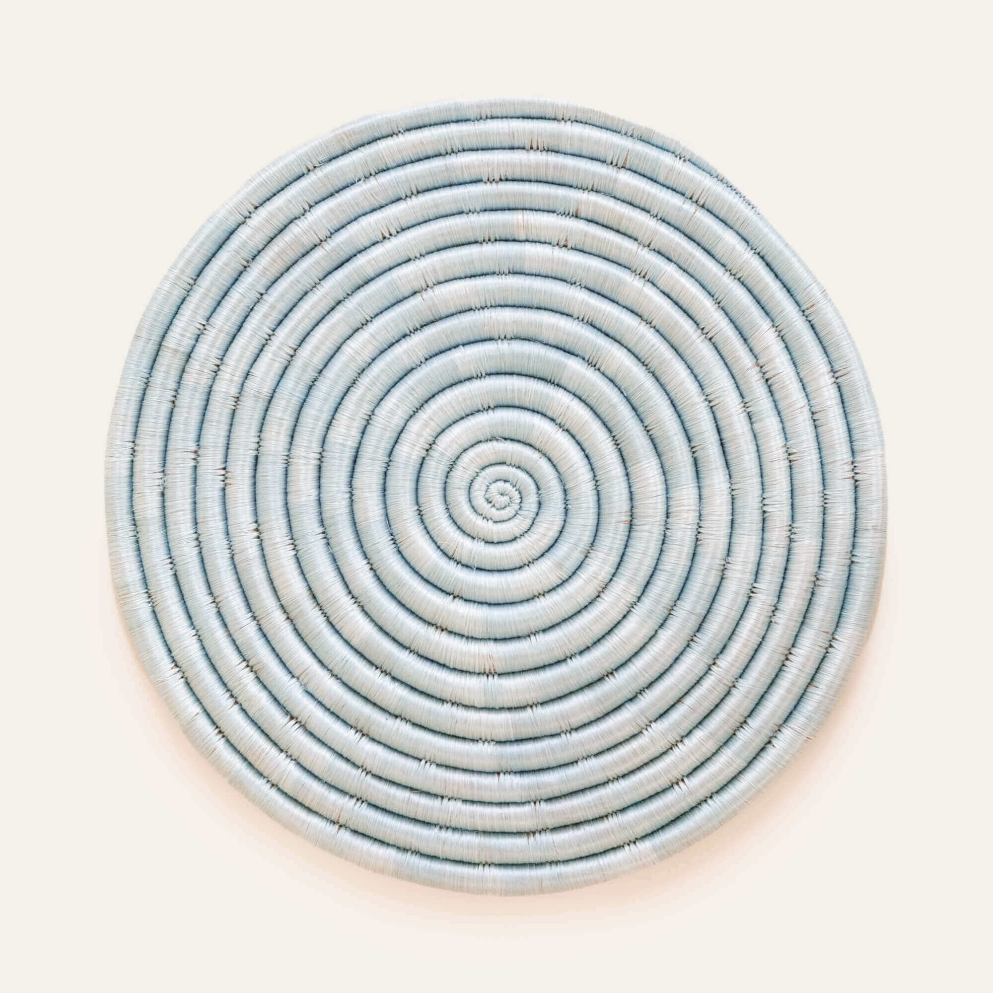 Light blue circular sisal placemat, handwoven with natural fibers for a stylish and functional table accent.