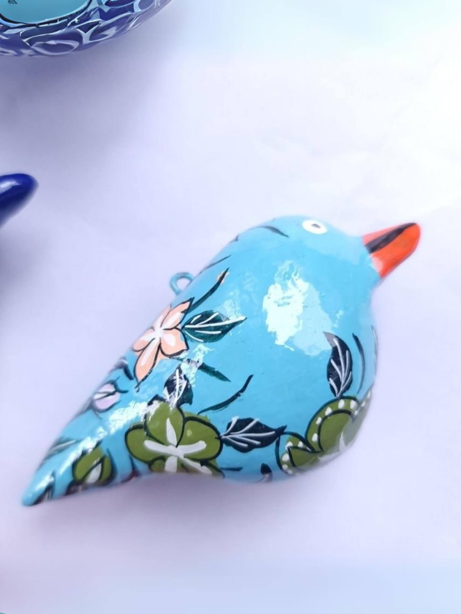 Decorative papier-mâché bird with floral pattern on a white background
