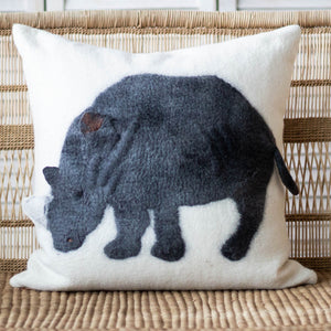 Decorative pillow with a rhinoceros design on a wicker chair.