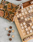 Wooden reversi game with circular pieces and a patterned cotton bag on a light surface