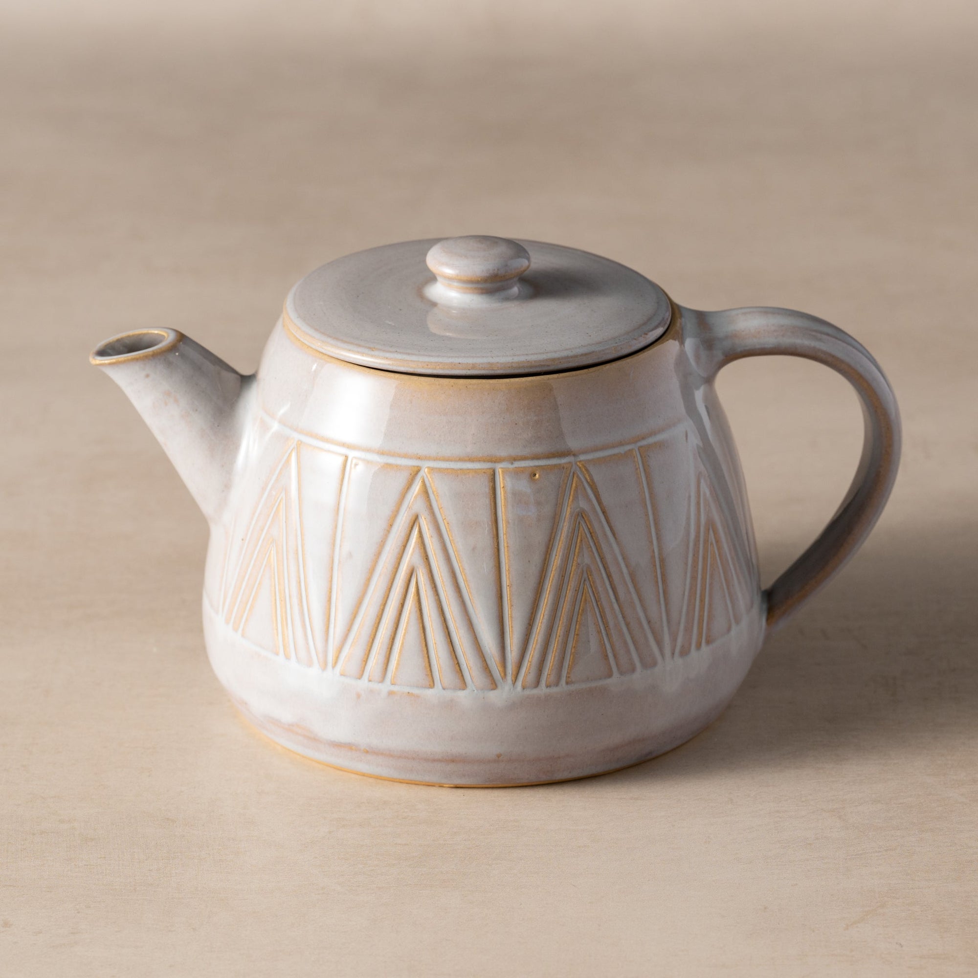 Ceramic teapot with geometric design on a beige background
